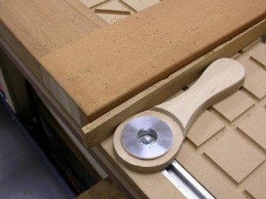 The cam action generates enough force to crush the soft mahogany. The shim protects the edge of the door but is not needed for clamping.